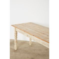 a wooden table sitting on top of a cement floor next to a white painted wall