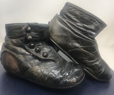 an old pair of black leather shoes sitting on top of a table