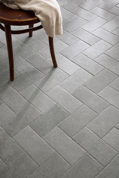 a chair sitting on top of a tile floor next to a table with a towel on it