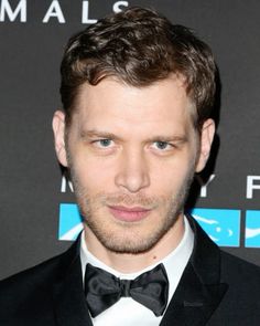 a man in a tuxedo and bow tie at an awards event looking to the side