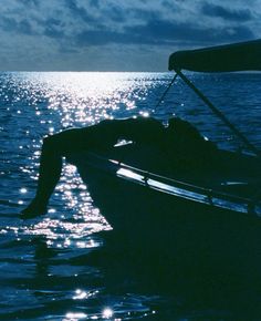 a man is floating in the water on a boat at night with his back to the camera