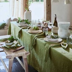 the table is set with green linens and place settings for two people to eat