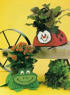 two potted plants sitting next to each other on top of a wooden bench with faces painted on them