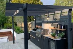 an outdoor kitchen with grill, sink and counter space under the pergolated roof