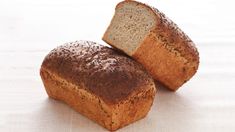 two loaves of bread sitting next to each other on a white tableclothed surface