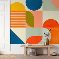 a table with vases and flowers in front of a colorful wall