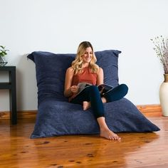 a woman sitting on a bean bag chair reading a book