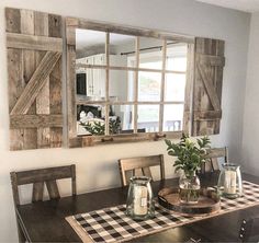 a wooden table topped with a vase filled with flowers next to a mirror on the wall