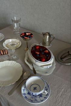 a table topped with plates and bowls filled with fruit next to a tea pot on top of a table