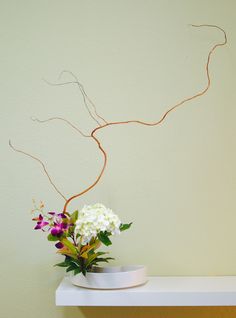 a vase filled with flowers sitting on top of a white table next to a wall