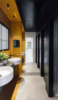 a bathroom with two sinks, mirrors and black cabinets on the wall next to each other