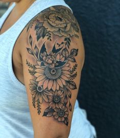 a woman's arm with flowers and birds tattoo on the back of her shoulder