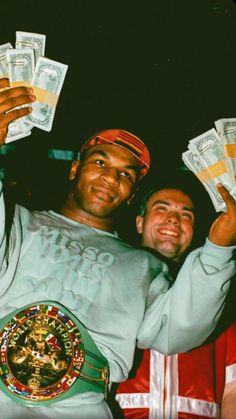 two men are holding up money in front of their faces and one is wearing a green belt