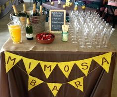 a table topped with lots of wine glasses and bottles next to a sign that says mimosa bar