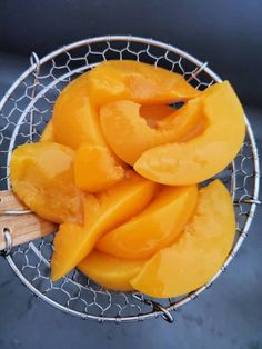 a metal bowl filled with sliced mangoes on top of a table