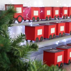 several red boxes are lined up next to a christmas tree in the shape of a train