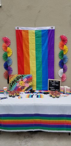 a table topped with lots of candy and rainbow colored paper fan decorations on top of it