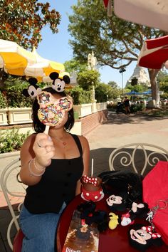 a woman sitting at a table with mickey mouse masks on her face and other decorations