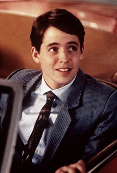 a young man in a suit and tie sitting in a car