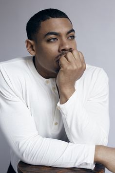 a man sitting at a table with his hand on his chin and looking off to the side