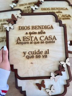 a person holding up a wooden plaque with butterflies on it that reads, dios bendiga a muerto aesta cas