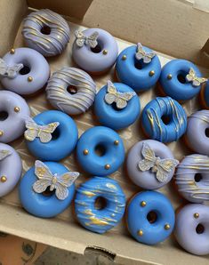 a box filled with blue and purple donuts covered in frosting next to each other