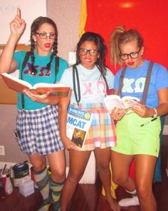 three girls are standing in front of a red wall and one girl is holding a book