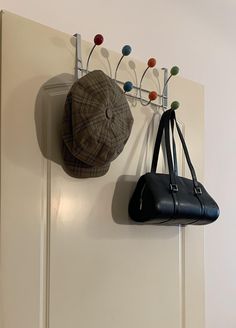 two hats are hanging on the wall next to a purse