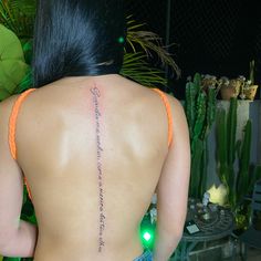 the back of a woman's body with a tattoo on her left shoulder and words written in cursive writing