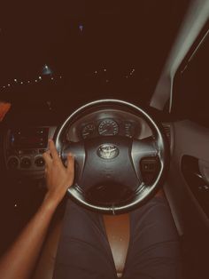 a person sitting in the driver's seat of a car with their hands on the steering wheel