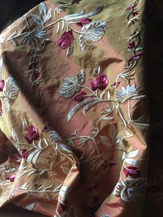 an image of a pink and gold fabric with flowers on it's back side