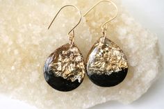 black and gold drop earrings on top of a white piece of rock with glittery details