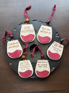 six wine tags with sayings on them sitting on top of a metal pan covered in red string