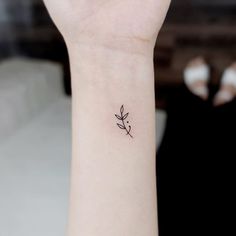 a small tattoo on the wrist of a woman's arm, with a single flower