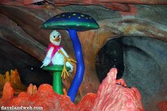 there is a fake bird sitting on top of a mushroom in the cave with rocks