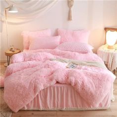 a bed covered in pink fluffy blankets and pillows