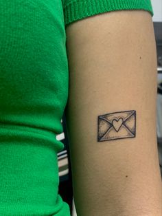 a woman's arm with a small envelope tattoo on the left side of her arm