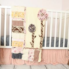 a white crib with a pink and brown quilt on it