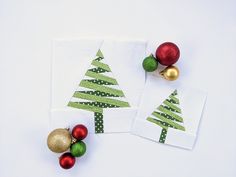 two napkins decorated with christmas trees and ornaments on white surface next to each other