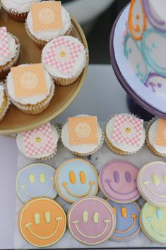 cupcakes with smiley faces on them are sitting next to plates and trays