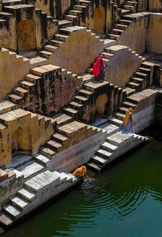 two people are standing on the edge of some steps next to a body of water