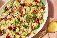 a white bowl filled with pasta and broccoli on top of a pink cloth