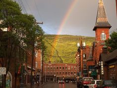 a rainbow shines in the sky over a city street