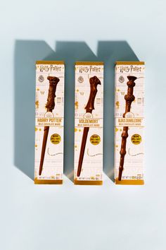 three harry potter wands are on display in their packaging boxes, one is brown and the other is white