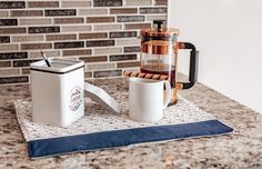 two coffee mugs sitting on top of a kitchen counter next to a blender