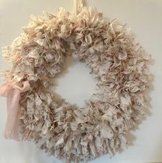 a wreath hanging on the wall with pink ribbon