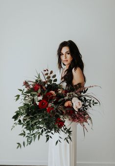 a woman holding a large bouquet of flowers in her hands and posing for the camera