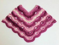 a pink crocheted shawl hanging on a wall