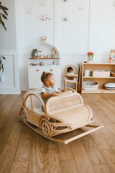 a small child is sitting in a wooden toy sleigh on the hardwood floor