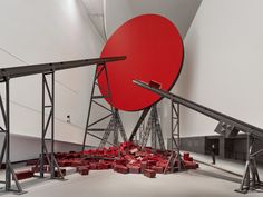 a large red object sitting on top of a white floor next to a tall metal structure